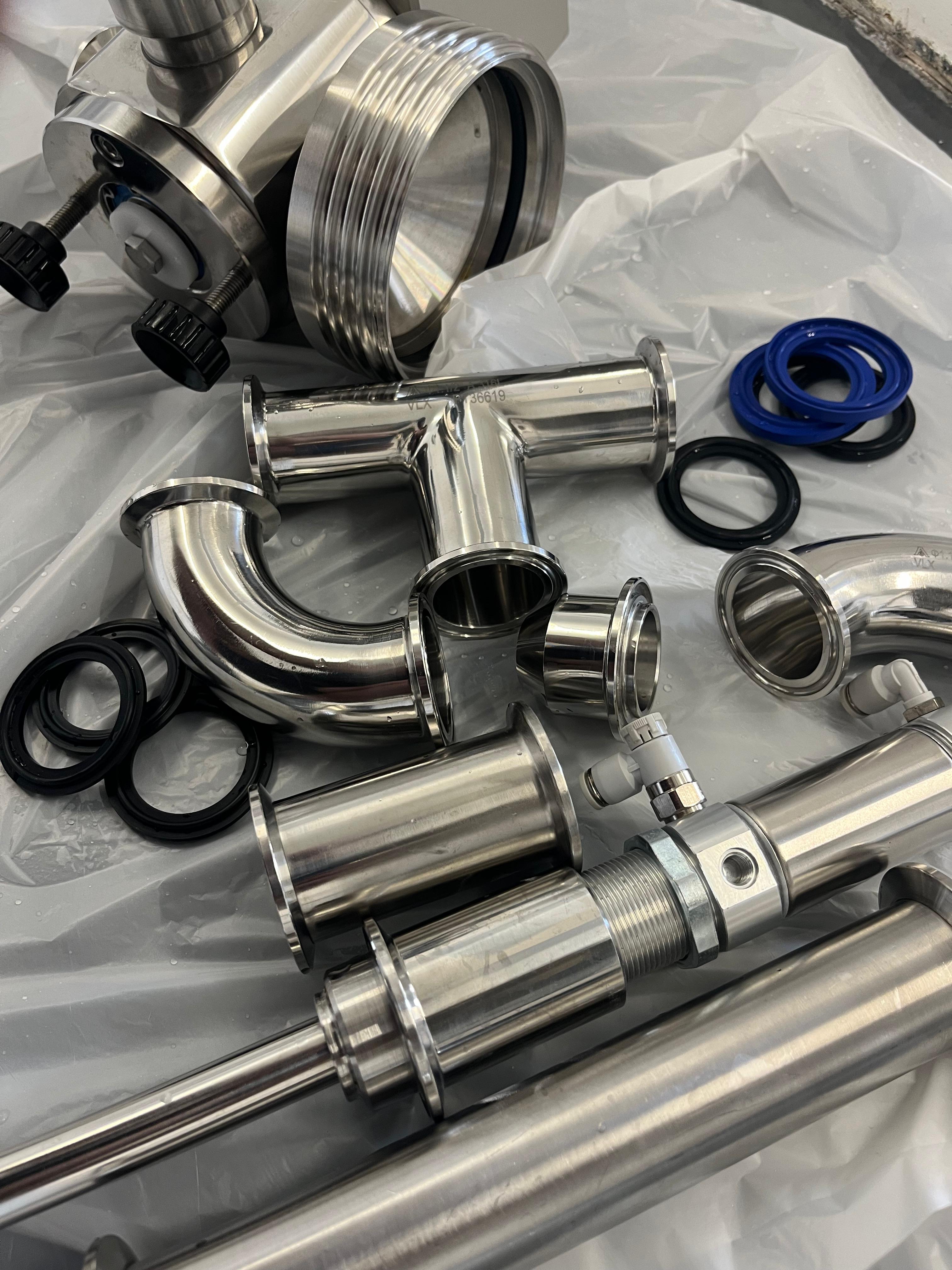 Stainless fill-line parts laid out for mechanical strip-down and deep clean between runs.